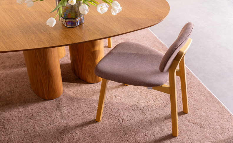 cadeira na black friday em uma sala de jantar em tons de marrom rosado, além de tapete e um vaso decorativo.