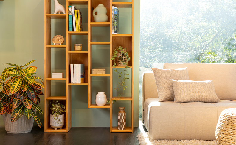 estante na black friday, um modelo com nichos vazados com diversos itens decorativos como vasos, adornos e livros em uma sala de estar com vaso de chão com planta e sofá.