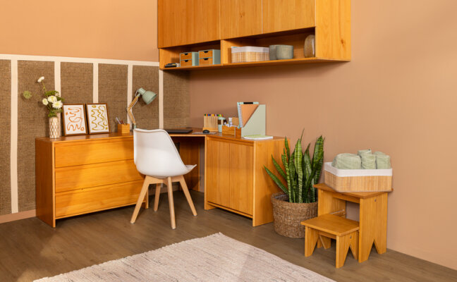 como decorar apartamento pequeno otimizando um espaço de home office no quarto com escrivaninha em L, cadeira, armário aéreo e itens decorativos.