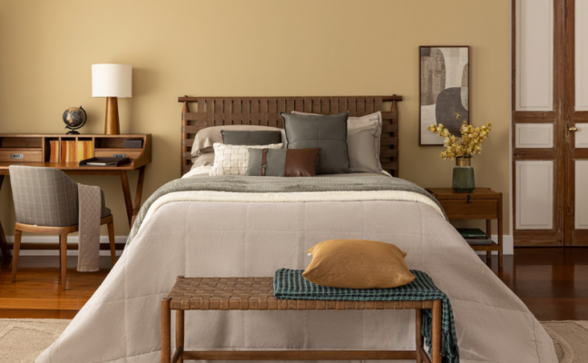 cama de casal em um quarto médio com diversos itens decorativos, cama posta em branco e cinza e cadeira