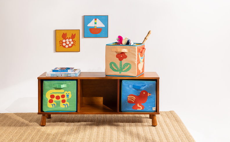 organizador quarto infantil com cômoda e caixas organizadoras práticas para guardar brinquedos por categorias, além de tapete e quadros decorativos.