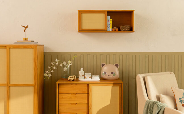 dicas de organização de quarto infantil com prateleira para quarto infantil, cômoda, guarda-roupa e poltrona, além de adornos decorativos, manta e vaso com flores.
