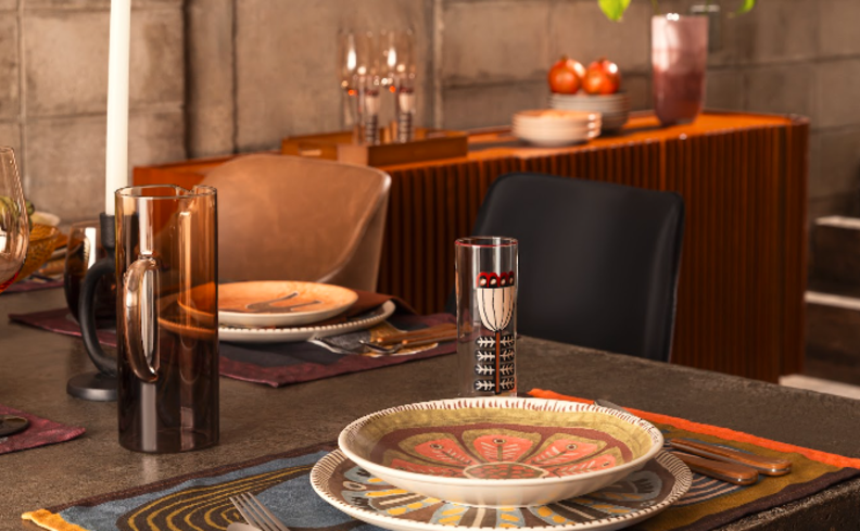 sala de jantar mesa posta com pratos, taças, copos e diversos itens decorativos.