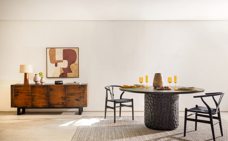sala de jantar moderna com mesa de jantar redonda, duas cadeiras, aparador de madeira, quadro e itens de decoração.