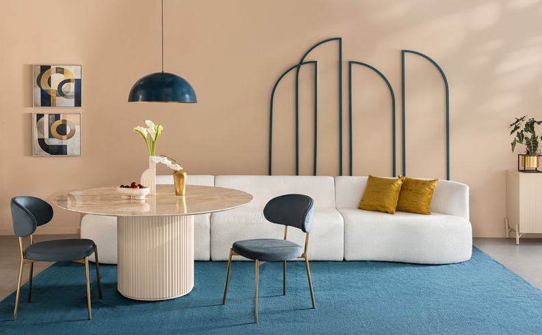 sala de jantar simples e bonita com tons de branco e azul, com mesa redonda, duas cadeiras na cor azul, lustre pendente, sofá e tapete.