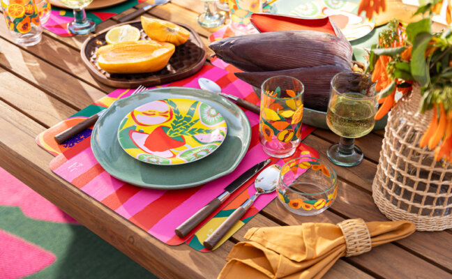 mesa posta com decoração de verão com pratos estampados, copos, taças, guardanapo e muito mais