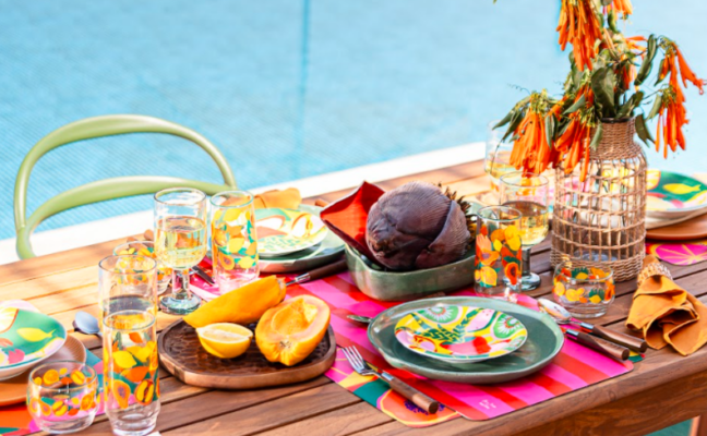 mesa posta de verão com diversos pratos, copos, enfeites de mesa e frutas