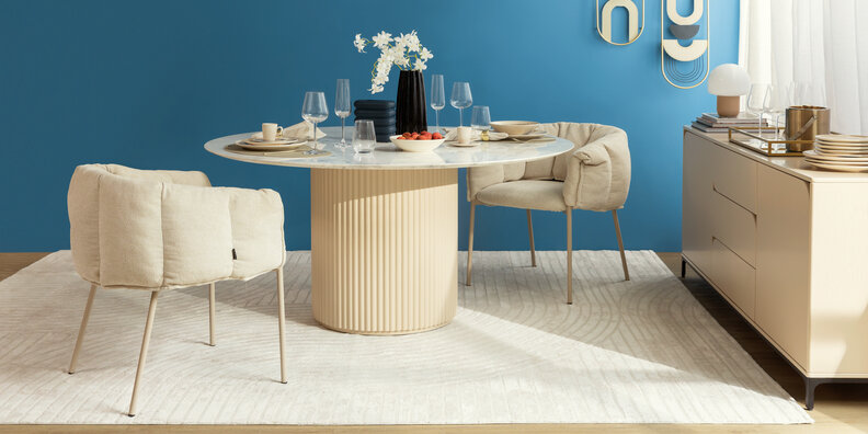 opções de modelos de mesa de jantar com uma mesa redonda, duas cadeiras brancas com braços, tapete branco, lustre pendente, buffet ao lado para complementar a decoração e deixar o ambiente organizado e funcional.