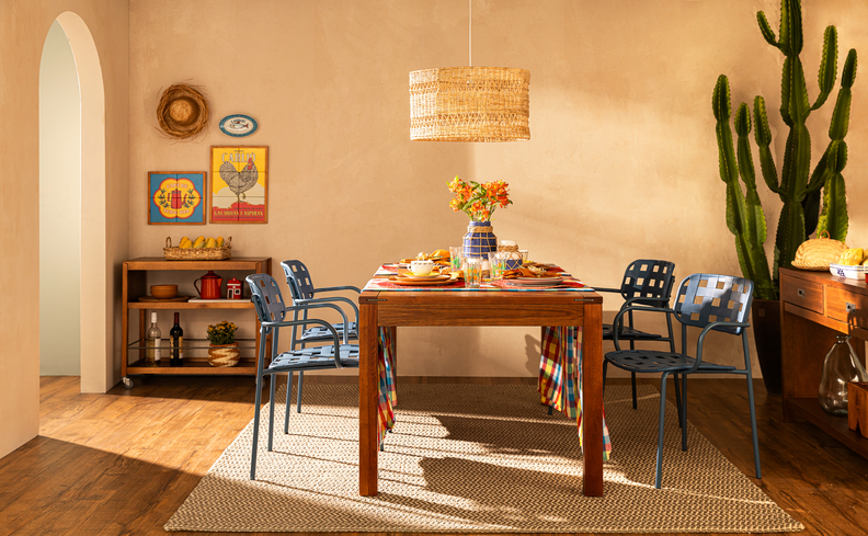 enfeites de mesa para festa junina com mesa posta completa na sala de jantar, mesa de madeira, cadeiras azul, tapete, aparador e diversos itens decorativos.