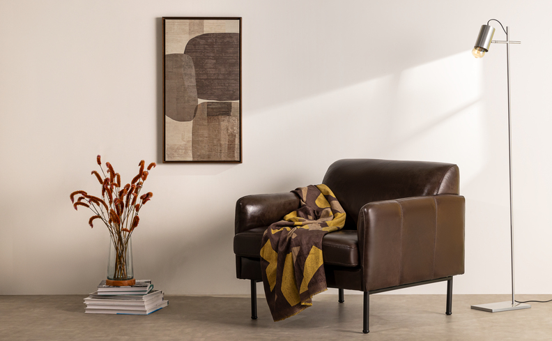 decoração cantinho da leitura com poltrona, manta, vaso decorativo com flor, luminária de chão e quadro decorativo