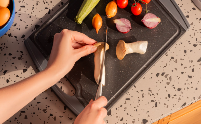 pessoa cortando alimentos com uma faca e sabendo a importância entre afiar e amolar faca