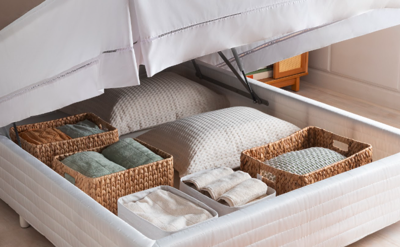 organizador de gaveta quarto com uma box baú com diversas cestas de palha decorativas, com roupas de cama, toalhas e outros itens menos usados no dia a dia.