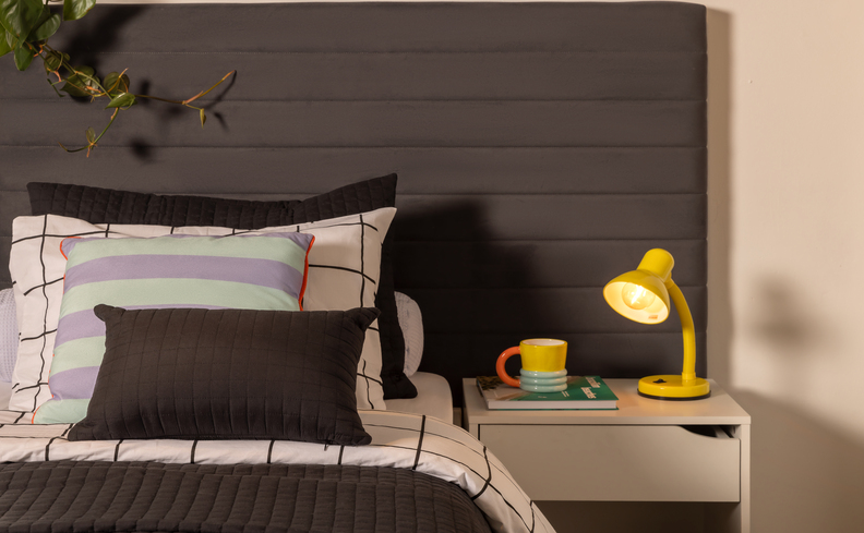 quarto com mesa de cabeceira e uma luminária de mesa em cima