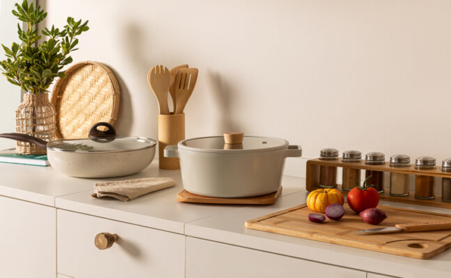 bancada de cozinha com duas panelas para fogão de indução, com tábua, alimentos e utensílios de cozinha
