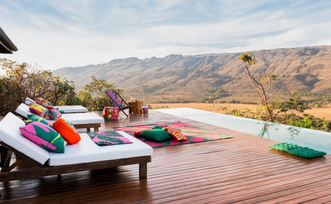 chaise para jardim na área externa com almofadas, piscina e outros itens