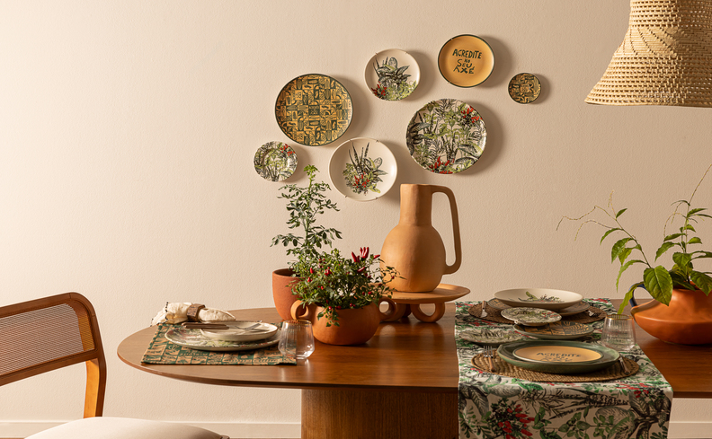 sala de jantar com mesa retangular, cadeira, pratos na parede e vários tipos de cachepot para plantas e vasos sobre a mesa