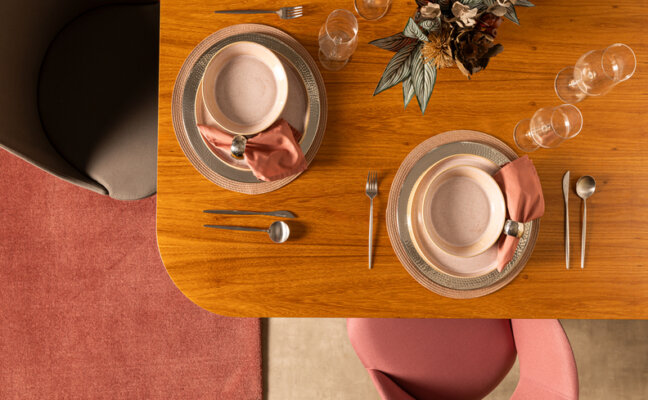 mesa posta com aparelho de jantar com pratos rasos e fundos, além de taças e outros itens