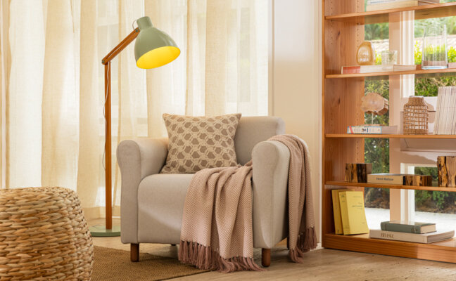 como deixar a casa mais aconchegante com uma poltrona, luminária de chão, manta para sofá, almofadas, tapete e estante
