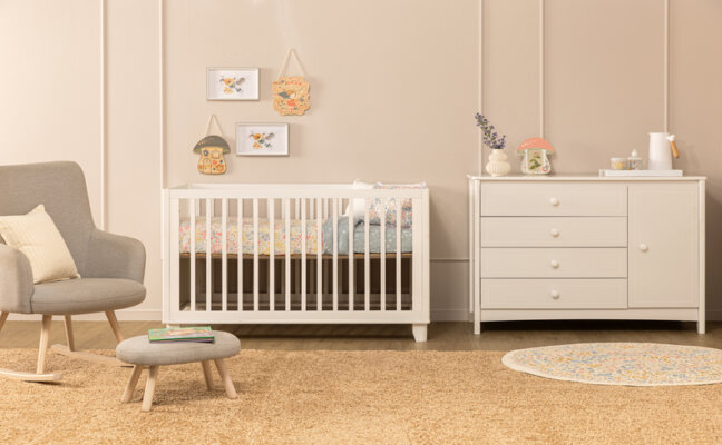 quarto pequeno de bebê com poltrona, berço, cômoda, mesa de apoio e diversos itens decorativos