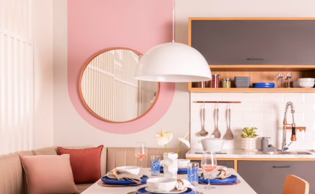 tons de rosa para parede, além de estar presente na mesa posta e nas almofadas do canto alemão, ambiente com mesa, pendente, espelho e armário de cozinha