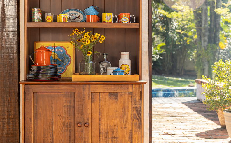 casa decoração rústica com cômoda de madeira om xícaras, bandeja, quadros e outros detalhes decorativos