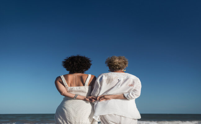 o que dar de presente de dia das mães, mãe e filha de costas abraçadas observando o mar