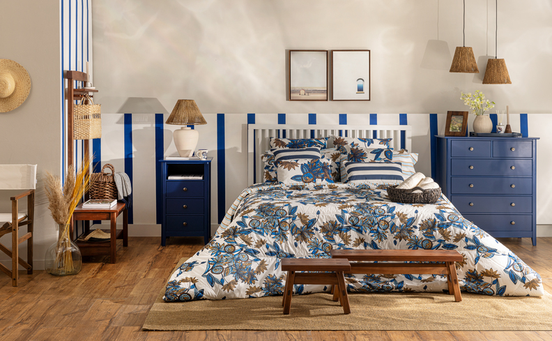 quarto em tons de azul na roupa de cama, na mesa de cabeceira e na cômoda combinando com tons de palha e branco