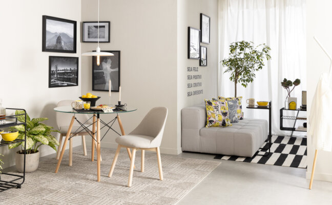 sala cinza e branco com sofá cinza, mesa de vidro e madeira, além de cadeira branca e detalhes decorativos em preto