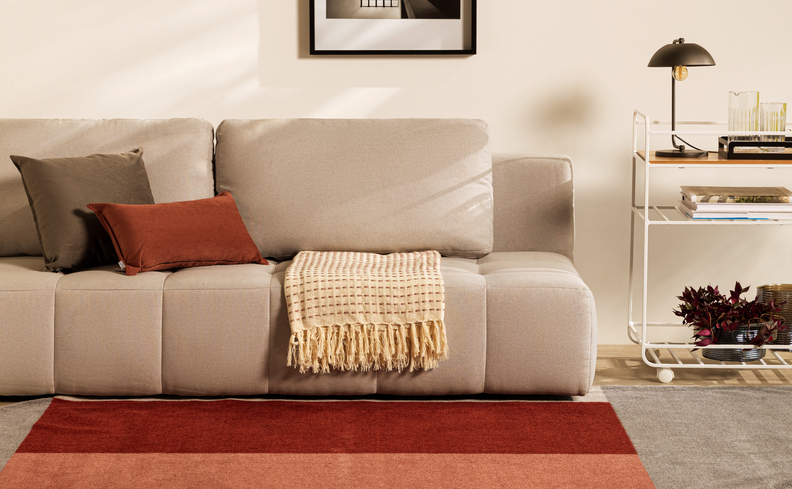 sofá branco para sala de estar, com detalhes coloridos como almofadas, manta para sofá e tapete