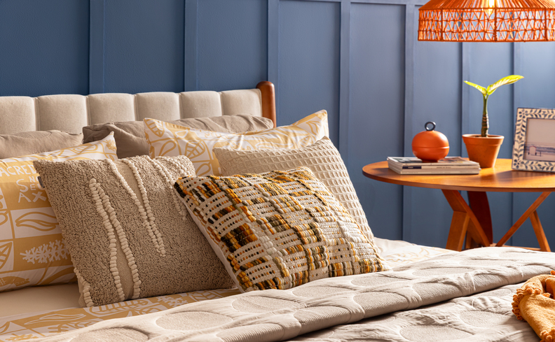 como deixar o quarto aconchegante com travesseiros e almofadas sob a cama, além de itens decorativos no ambiente