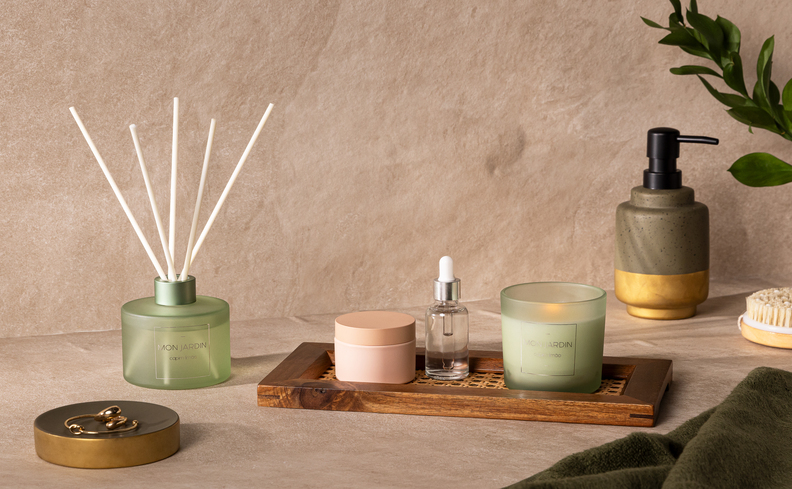 decoração estilo romântico no banheiro com itens em tons de verde claro como difusor de ambiente, vela aromática, entre outros.