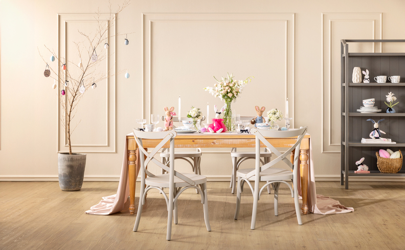 decoração romântica na sala de jantar com mesa, cadeiras, vaso com galho seco e estante com diversos itens decorativos.