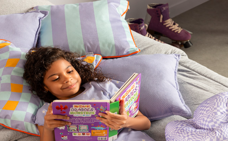 menina deixada em um quarto lendo um livro com um patins ao lado, que é uma boa opção de esportes para crianças de 10 anos ou mais.