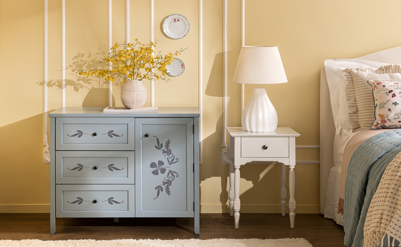estilo romântico na decoração com cômoda em tons de azul pastel, mesa de cabeceira branca e luminária em um quarto.