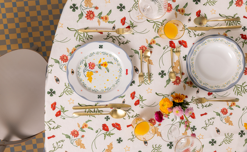 mesa posta romântica com toalha de mesa com estampa de flores, pratos, talheres e taças.