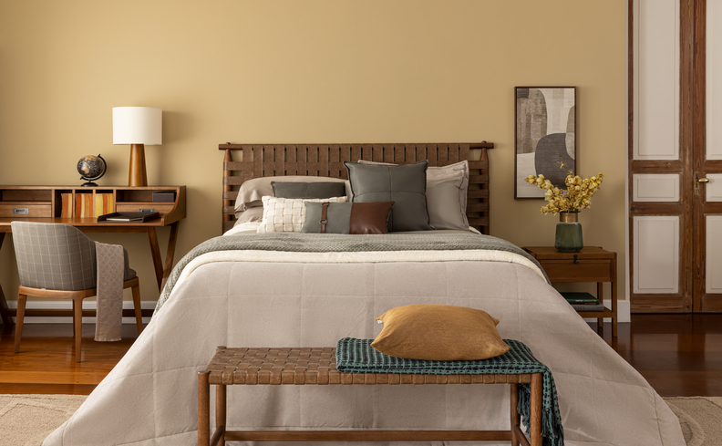 quarto aconchegante com cama queen, roupa de cama branca, escrivaninha, mesa de cabeceira e itens de decoração