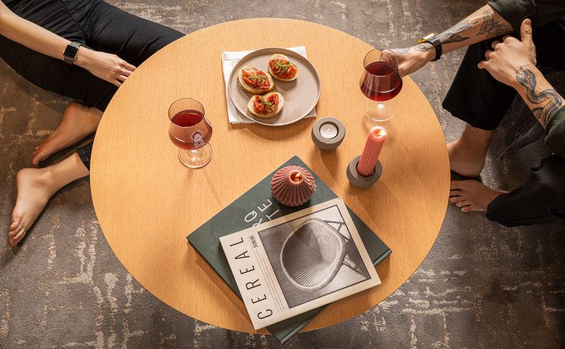 duas pessoas sentadas próximas a uma mesa de centro com taças de vinho e petiscos
