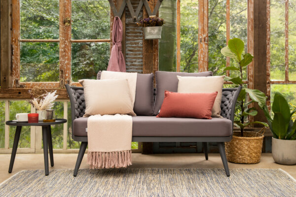 decoração de inverno na área externa com sofá, manta para sofá, almofadas, tapete e mesa lateral com diversos itens decorativos