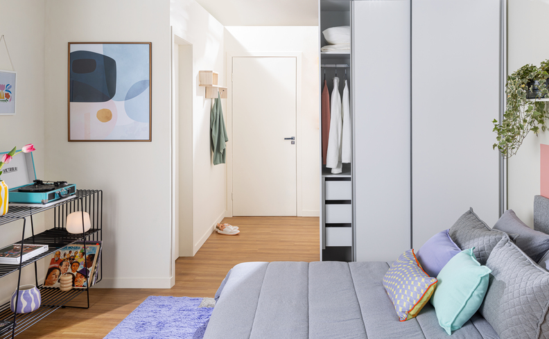 ambiente com guarda-roupa casal porta de correr, aparador, itens decorativos, cama e tapete