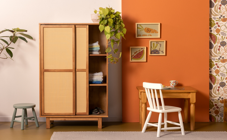 quarto com guarda-roupa infantil, além de escrivaninha, cadeira e diversos itens decorativos como plantas e quadros.