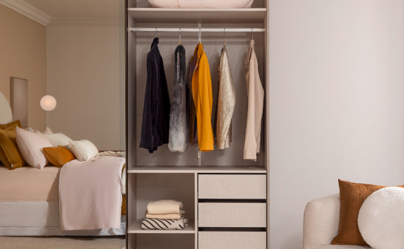 guarda-roupa solteiro com espelho com uma porta aberta mostrando o interior do móvel com diversos casacos pendurados, além de gavetas e nichos.