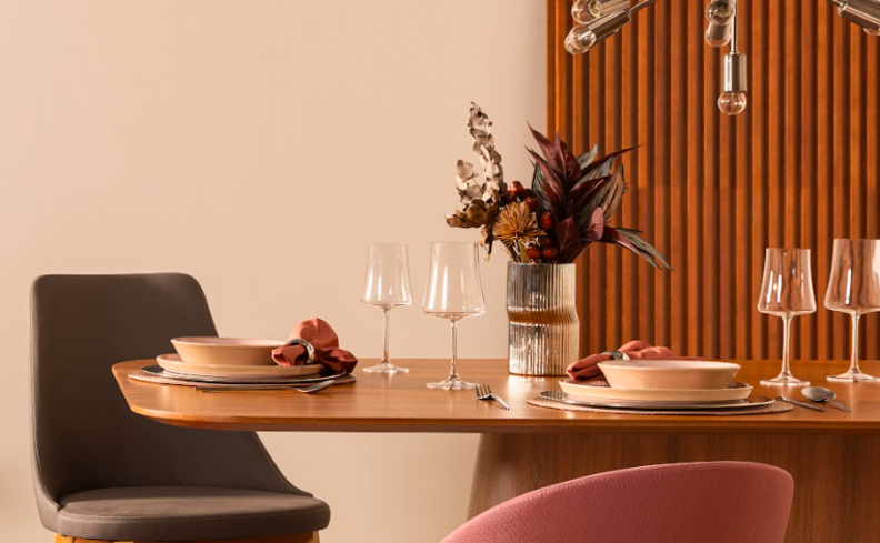mesa posta completa com taças para vinho, pratos, talheres e vaso decorativo com plantas