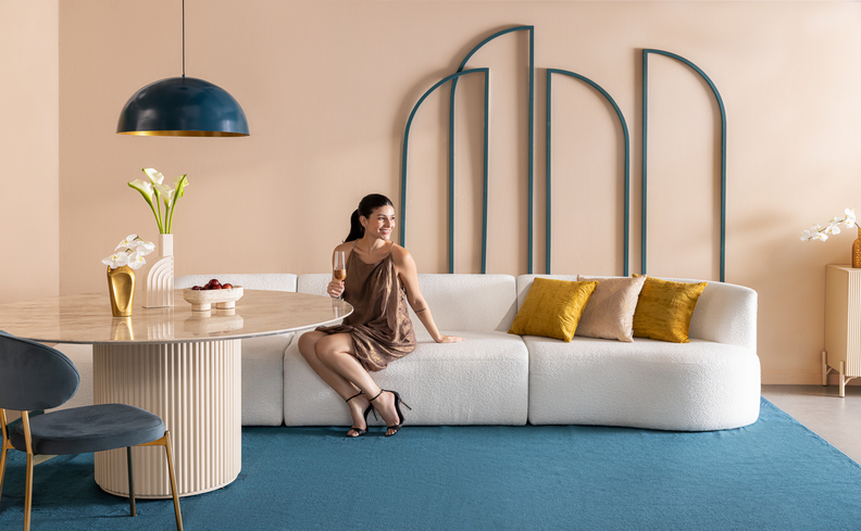 como decorar sofá com manta e almofada em uma sala de estar com sofá branco, almofadas coloridas, tapete azul e mesa de jantar com uma cadeira.
