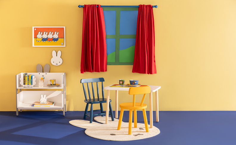 brincadeiras para o dia das crianças em um quarto colorido com mesa, cadeiras, cômoda e cortina vermelha.