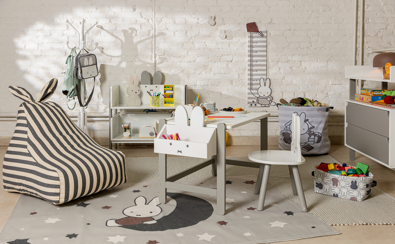 dicas do que fazer no Dia das Crianças em um quarto infantil com mesa, cadeira, puffe e diversos itens decorativos de coelho.