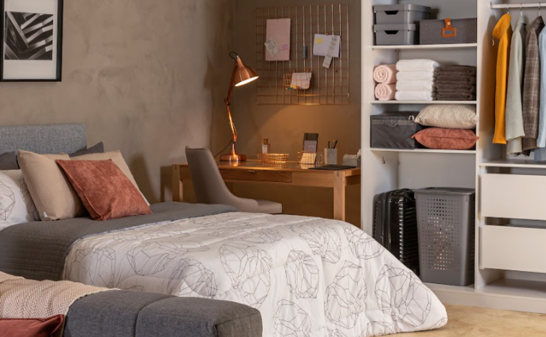 ideias para organizar sapatos no guarda-roupa em um quato de casal com cama, almofadas, travesseiros, edredom, escrivaninha e cadeira.