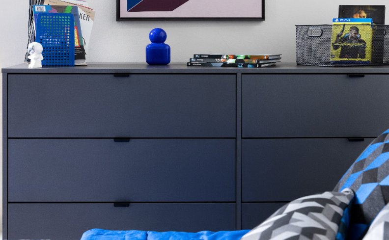 quarto adolescente em tons de azul com cômoda cinza, com diversos itens decorativos em tons de azul.