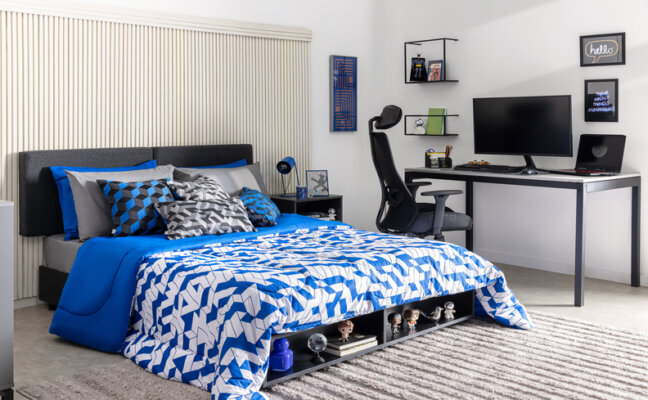 quartos de adolescentes com cama e roupa de cama em tons de azul, com diversas almofadas e travesseiros, além de escrivaninha, cadeira gamer, quadros decorativos e tapete.