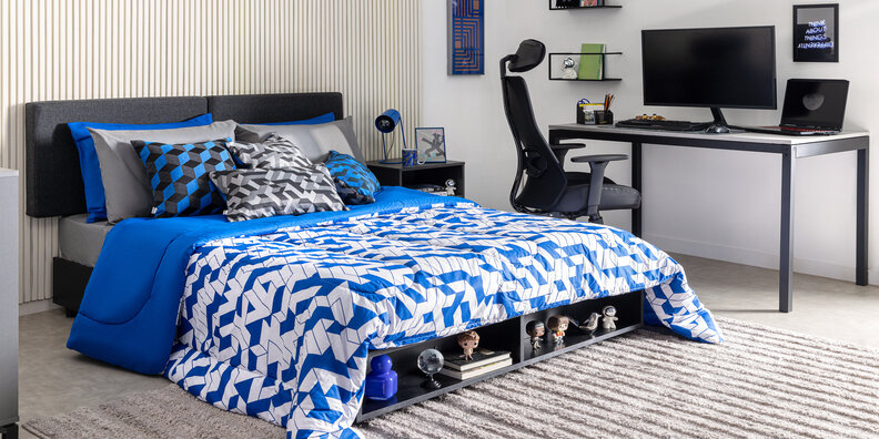 quartos de adolescentes com cama e roupa de cama em tons de azul, com diversas almofadas e travesseiros, além de escrivaninha, cadeira gamer, quadros decorativos e tapete.