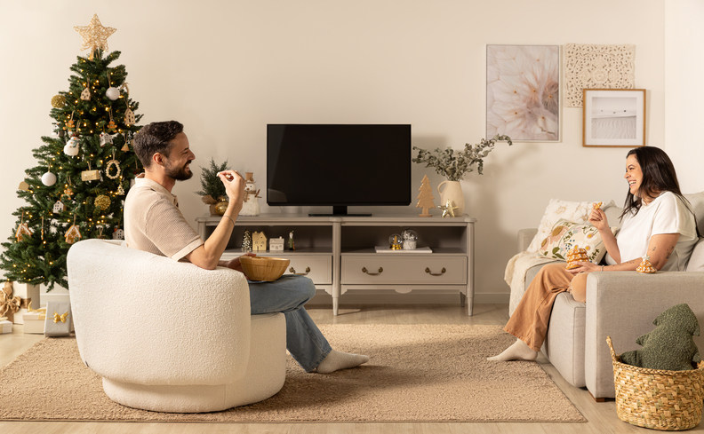 amigo secreto natal é uma das opções de brincadeiras para natal em família com duas pessoas na sala de estar com decoração natalina e conversando para trocar os presentes.
